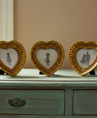 Three heart-shaped picture frames on a wooden surface with a plant and book in the background.