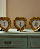 Three heart-shaped gold frames on a wooden surface with a neutral background