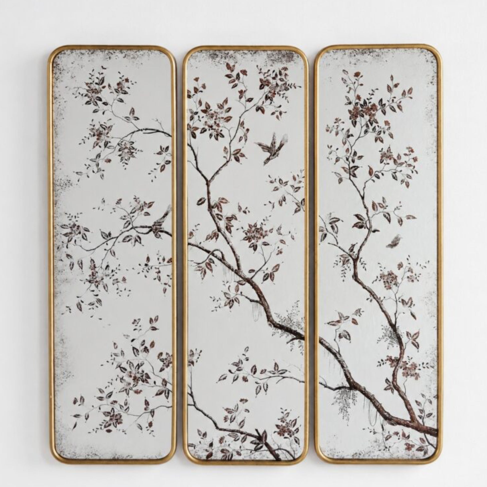 Three vertical rectangular wall panels with a gold-toned frame, featuring a delicate botanical branch and bird pattern in brown and muted tones on a distressed off-white background.