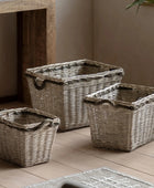 Three woven baskets of different sizes on a wooden floor.