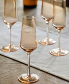 Set of four smoked glass champagne flutes on a wooden surface