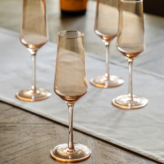 Set of four smoked glass champagne flutes on a wooden surface