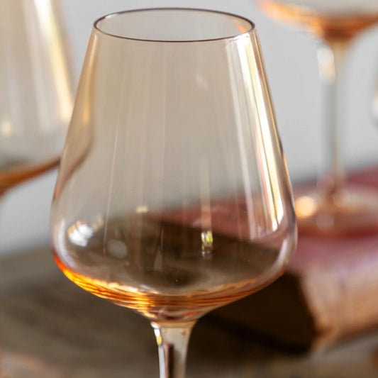 Clear wine glass with a warm tint on a wooden surface