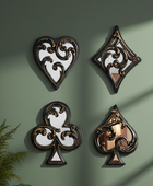 Decorative wall art pieces shaped like playing card suits on a green wall.