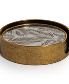 A round metallic tray with a textured gold finish and a clear glass top featuring an etched palm leaf pattern, shown on a white background.