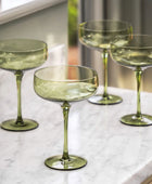 Set of four green glass stemware on a marble surface
