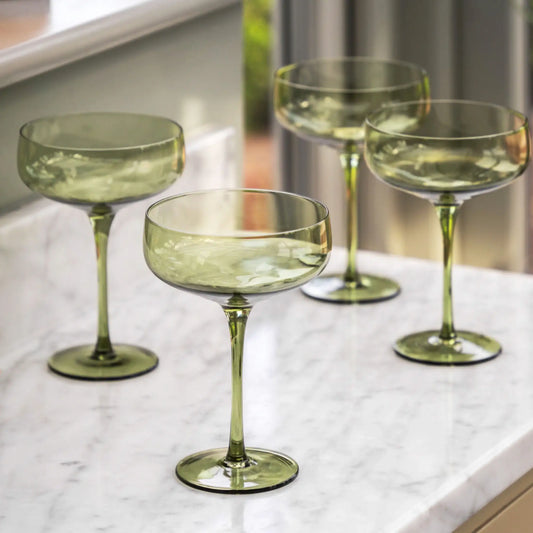 Set of four green glass stemware on a marble surface