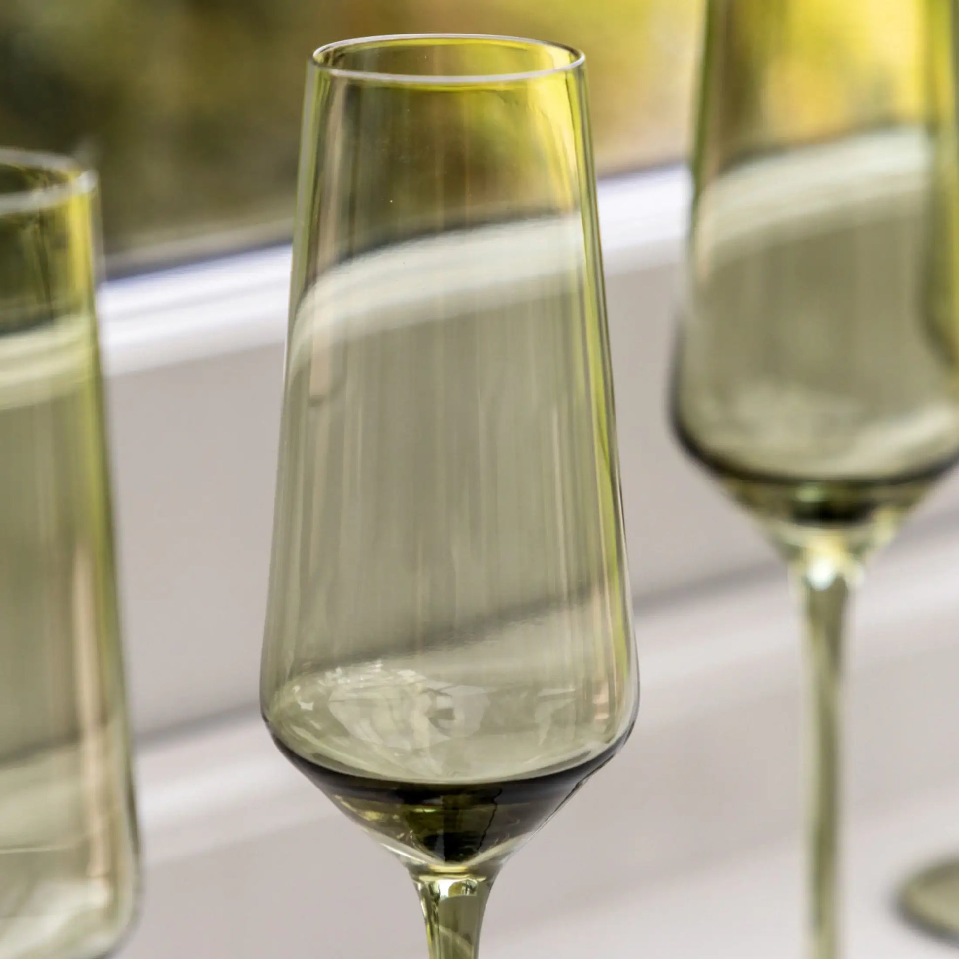 Green glass flutes on a white surface with a blurred background