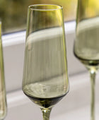 Green glass flutes on a white surface with a blurred background