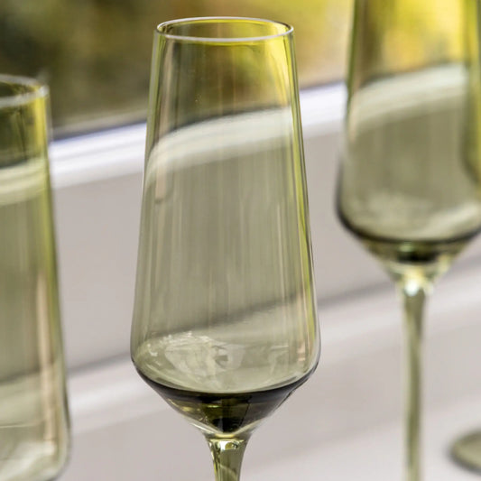Green glass flutes on a white surface with a blurred background