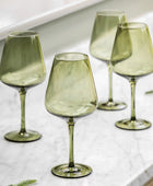 Set of four green wine glasses on a marble surface