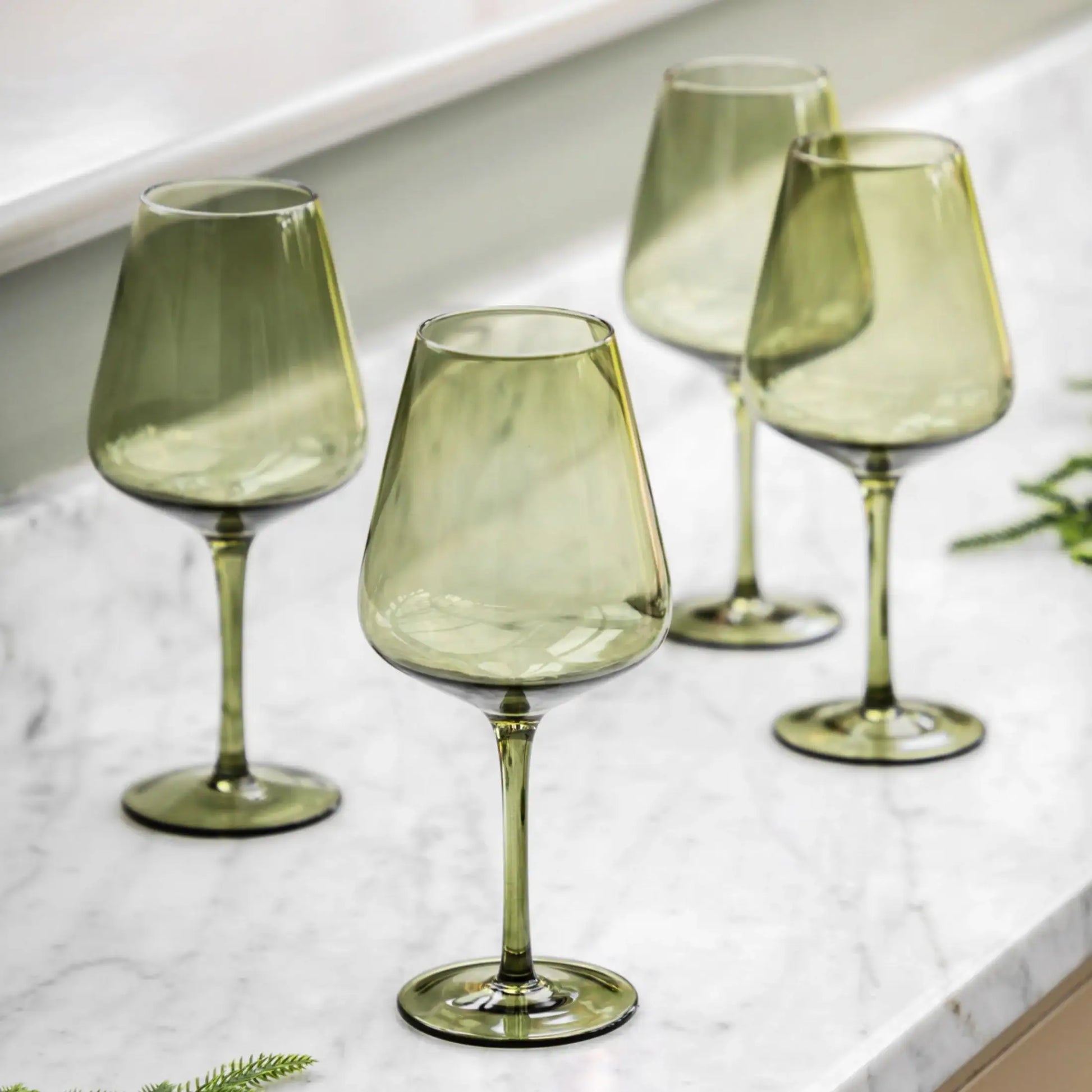 Set of four green wine glasses on a marble surface