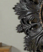 Decorative metal wall piece with intricate designs on a beige background