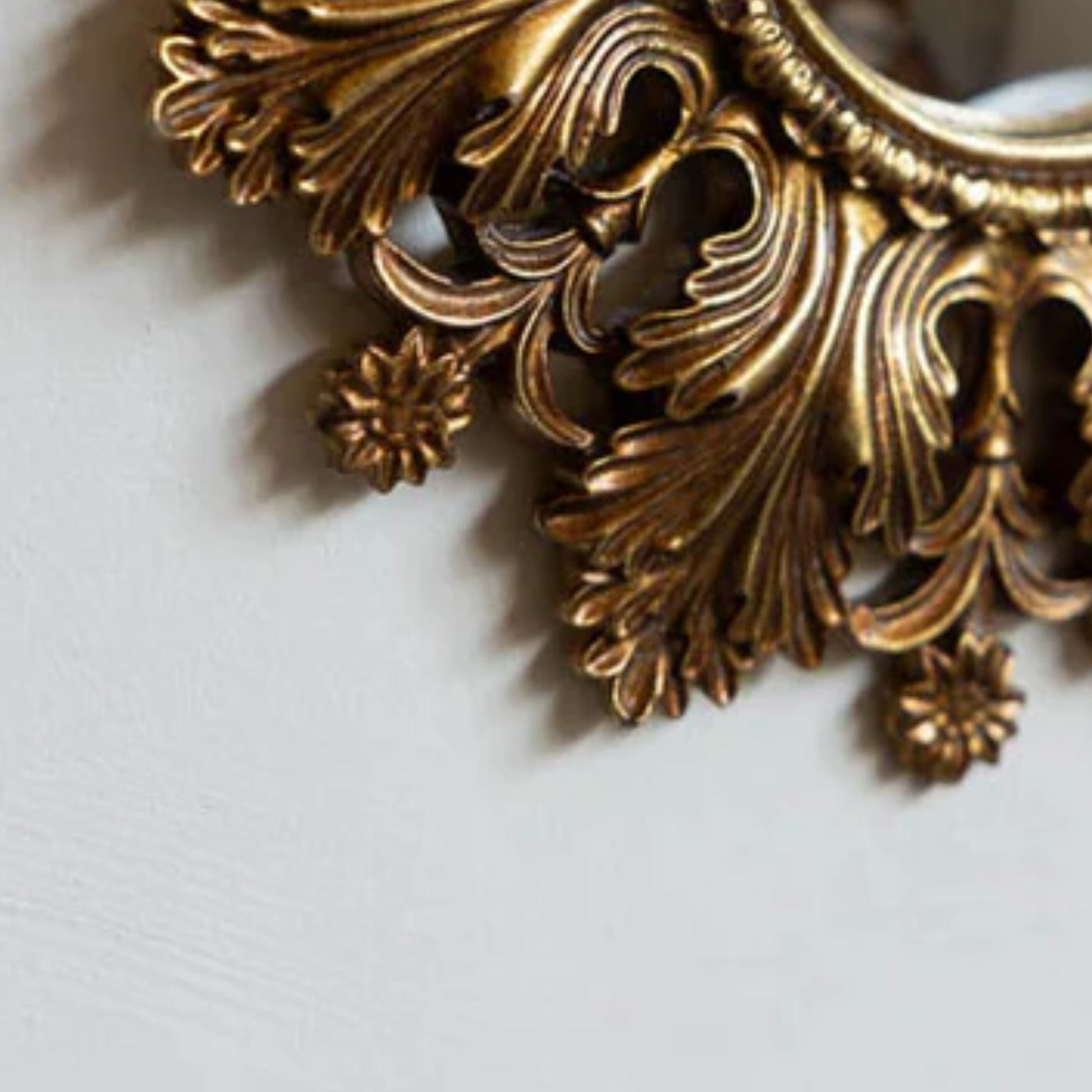 Decorative gold metal piece with intricate designs on a light gray background