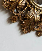 Decorative gold metal piece with intricate designs on a light gray background