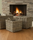 Wicker baskets on a wooden floor in front of a stone fireplace with a fire.