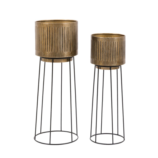Two decorative planters with metallic finishes on black wire stands against a white background.