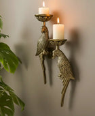 Bronze wall sconce with parrot designs holding candles against a neutral background