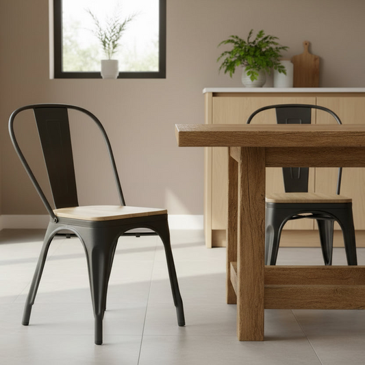 Dining area with wooden table and black metal chairs in a room with a window and plants.