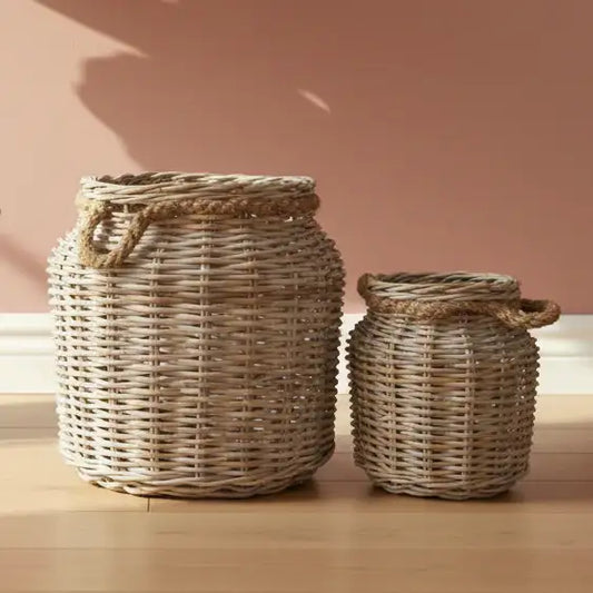 Two wicker baskets on a wooden surface with a pinkish-beige background
