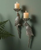 Decorative wall sconces shaped like parrots with candles on a green wall.