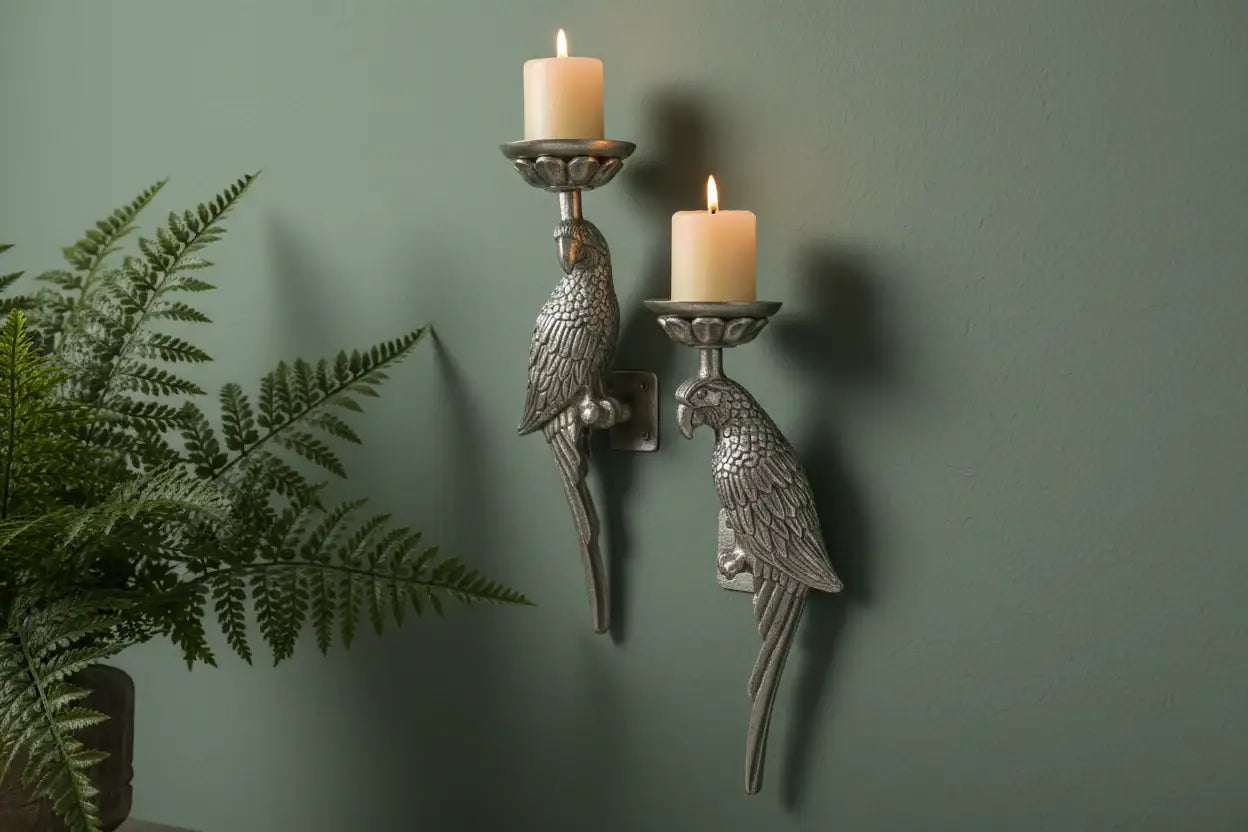 Decorative wall sconces shaped like parrots with candles on a green wall.