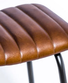 Close-up of a brown leather stool seat with a blurred background