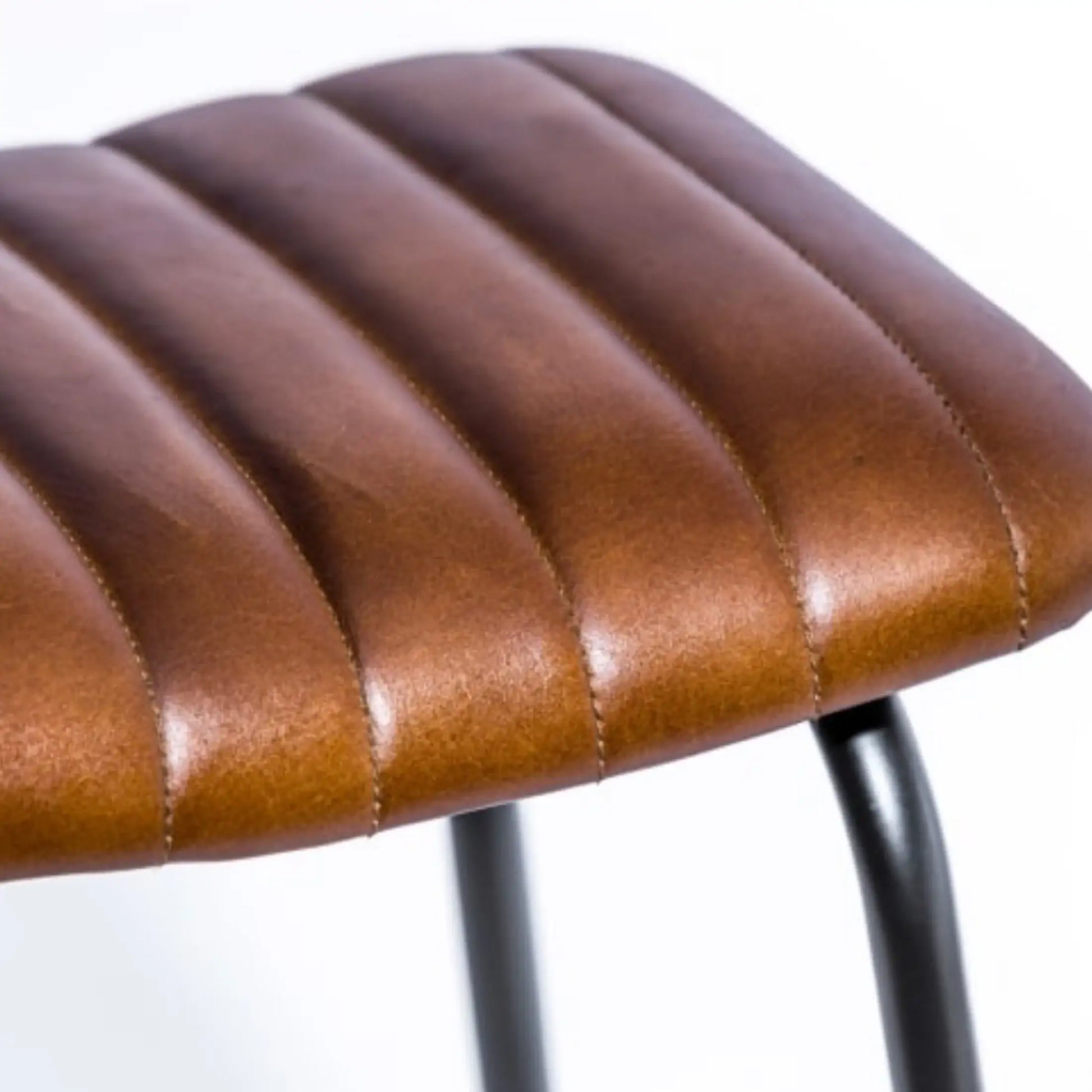 Close-up of a brown leather stool seat with a blurred background