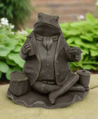 Statue of a frog in a suit holding a tea set on a white background