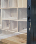 Close-up of a light natural wood shelving unit with multiple cubby compartments and a black metal frame with a handle on the right side.