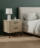 Wooden nightstand with lamp next to a bed in a bedroom setting