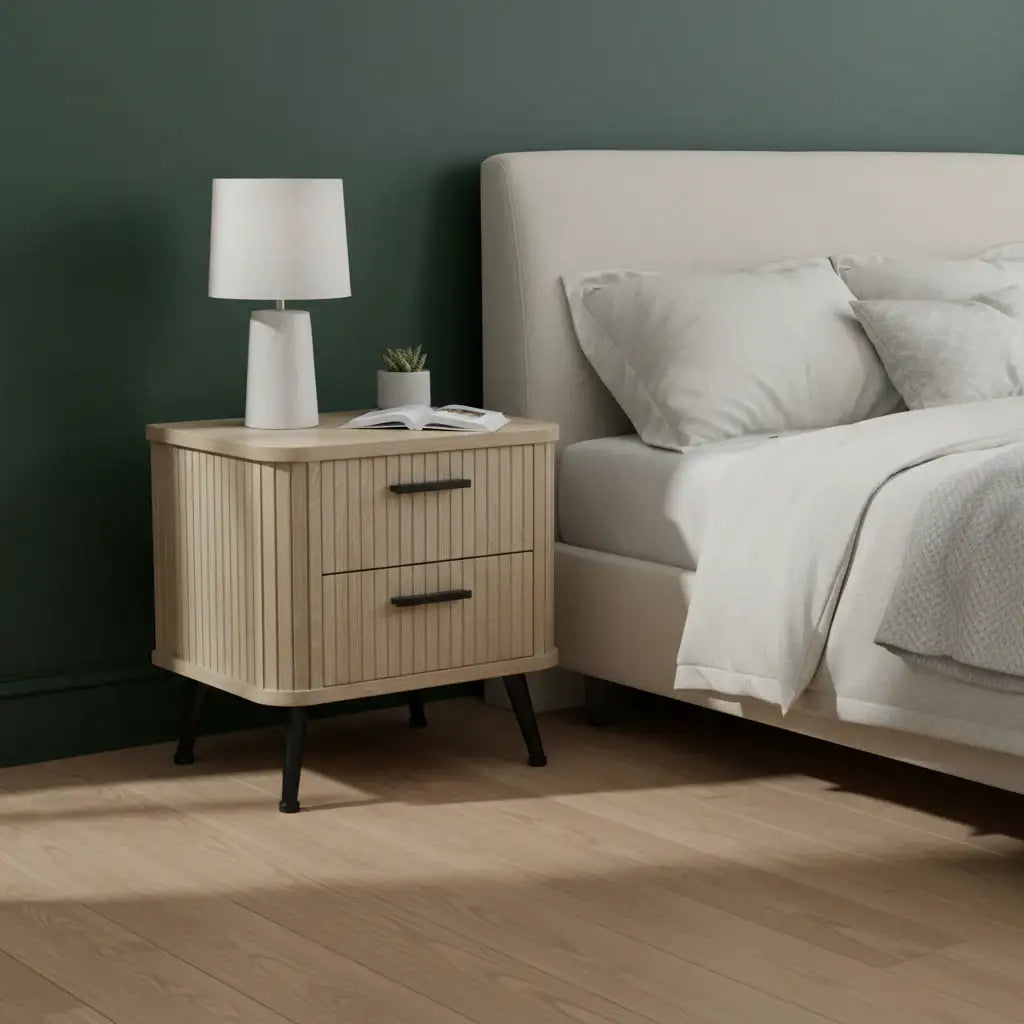 Wooden nightstand with lamp next to a bed in a bedroom setting