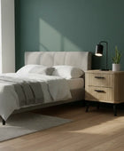 Modern bedroom with a bed, nightstand, and lamp against a green wall.