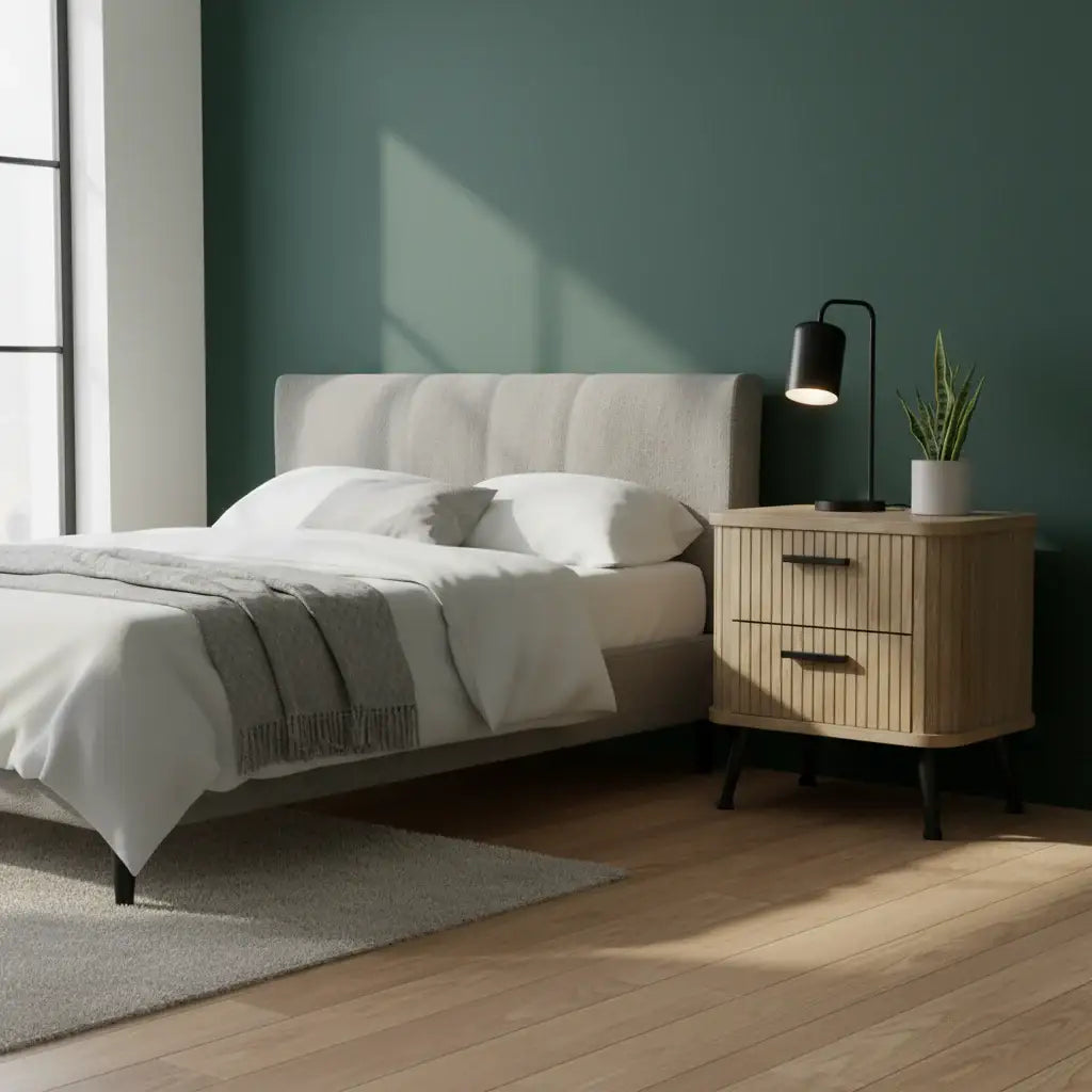 Modern bedroom with a bed, nightstand, and lamp against a green wall.
