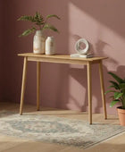 Wooden console table with decorative items against a pink wall