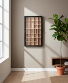 Wooden shelf with geometric design on a beige wall with a plant and rug in the foreground.
