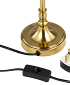 A close-up of a table lamp base in polished gold, with a black power cord, inline switch, and UK three-pin plug on a white background.