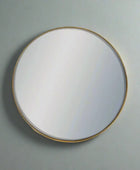 Round mirror with a gold frame on a gray wall
