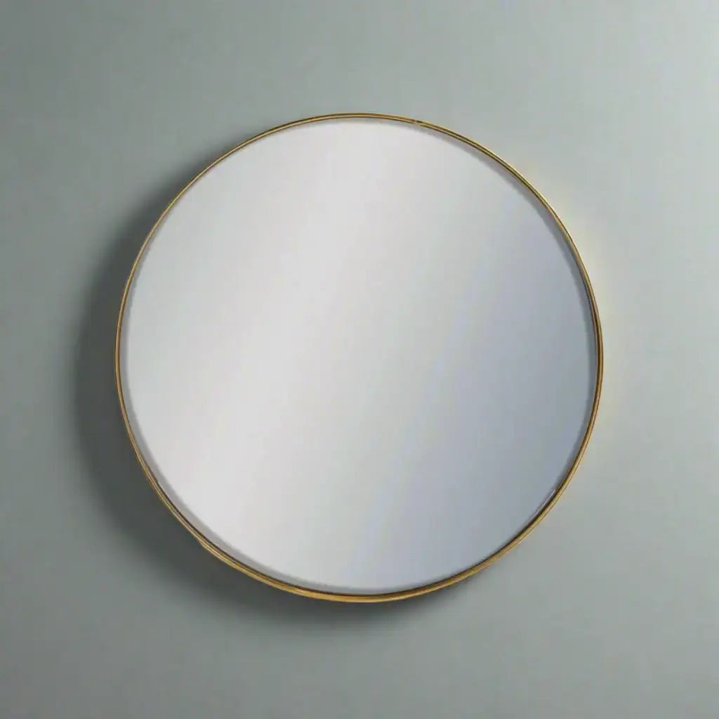 Round mirror with a gold frame on a gray wall