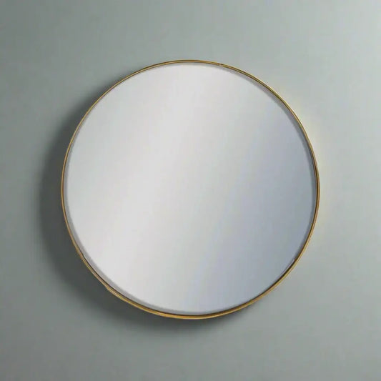Round mirror with a gold frame on a gray wall