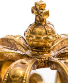 Close-up detail of an antique gold crown with a central globus cruciger and ornate rays, showing weathered patina against a white background.