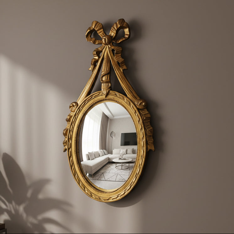 Decorative gold mirror with a bow on a wall