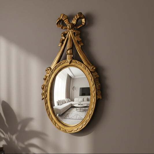 Decorative gold mirror with a bow on a wall