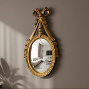 Decorative gold mirror with a bow on a wall