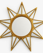 Decorative sun-shaped mirror with gold frame on a white background