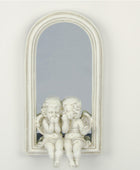 Decorative mirror with cherub sculptures on a white wall