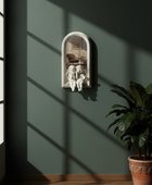 Decorative mirror with cherub figures on a green wall with sunlight casting shadows.