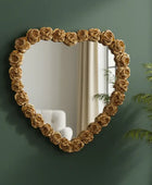 Decorative mirror with floral frame on a green wall