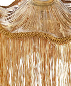 Close-up of a gold fringed textile or curtain with a decorative braided trim and sheer draped fabric above the fringe.