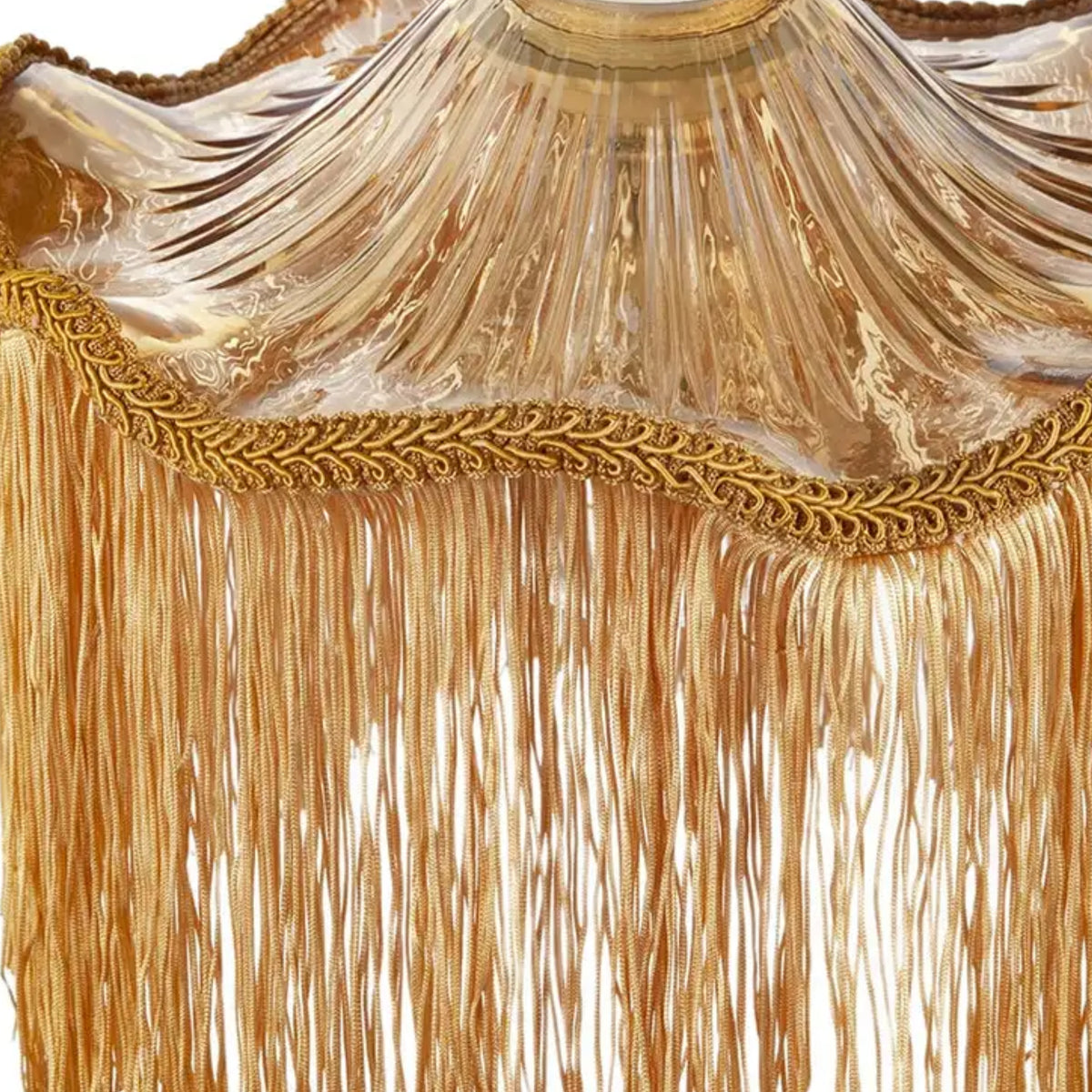 Close-up of a gold fringed textile or curtain with a decorative braided trim and sheer draped fabric above the fringe.
